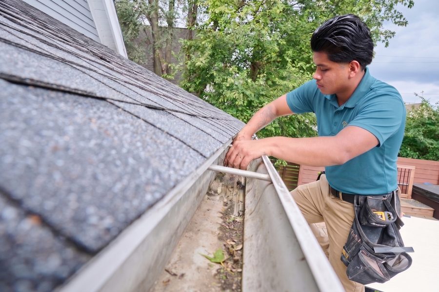 Ripple technician clearing debris from a roof gutter
